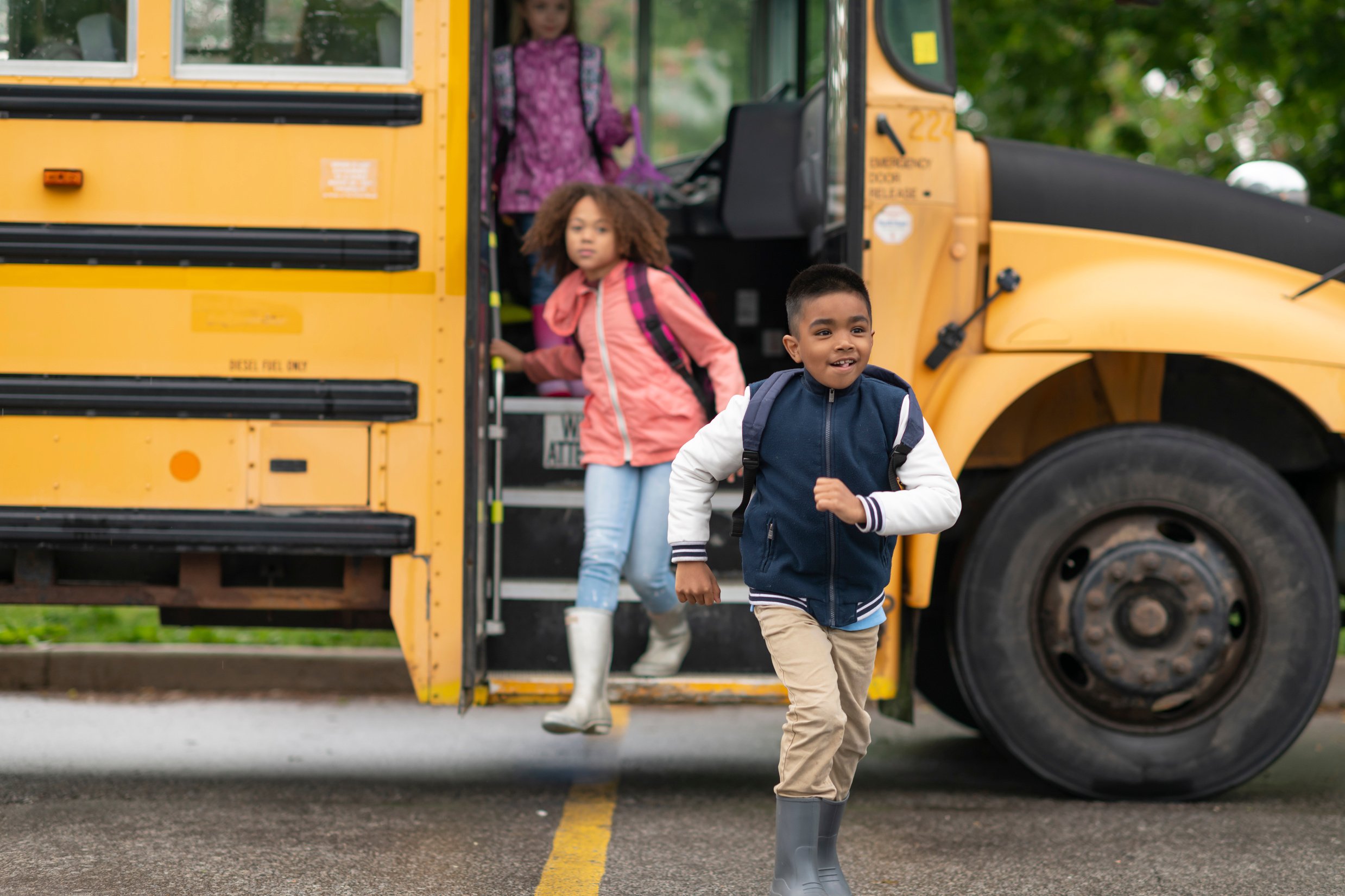 Happy elementary student getting off of school bus